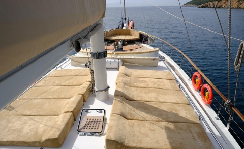 Sunlit open sea, wide deck on the yacht with beige sunbathing cushions