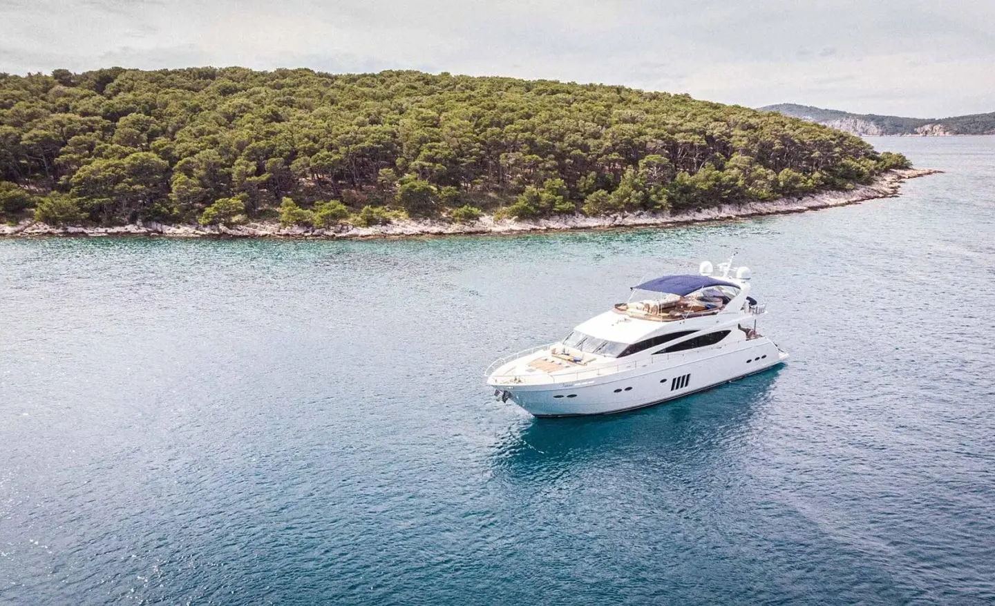 Insieme yacht anchored in calm blue water near rocky coastline