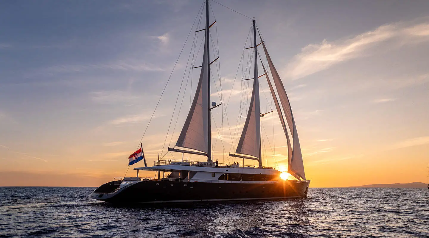 Nocturno luxury sailing yacht at sunset, two masts, dark hull, serene open sea panorama