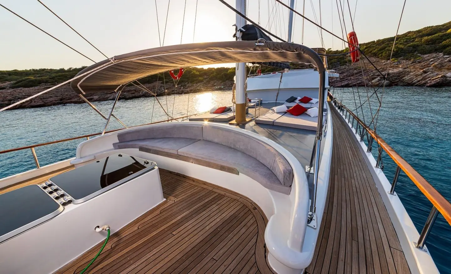 Bodrum Queen yacht on deck with curved lounge seating and sun pads at sunset