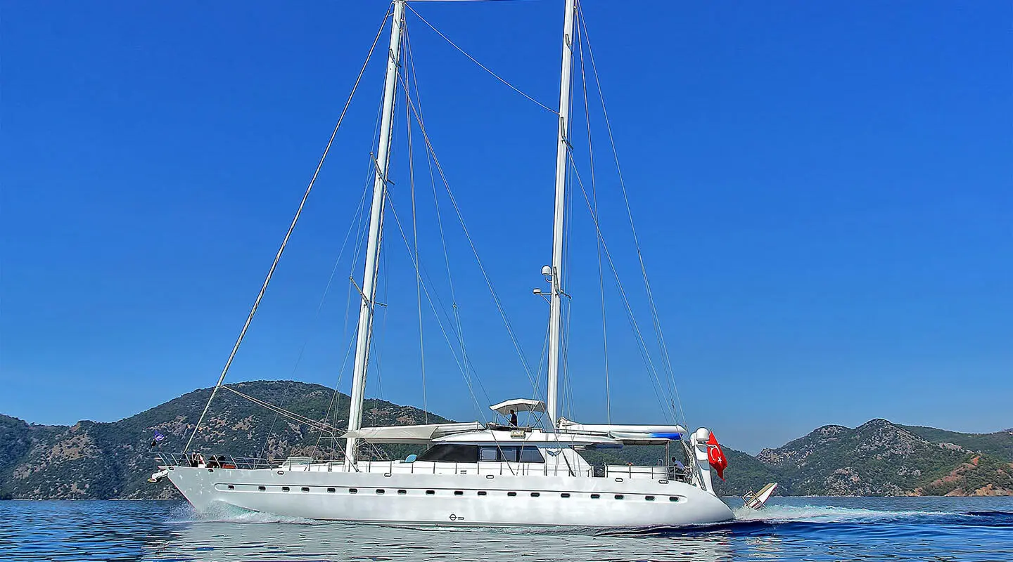 Angelo II yacht anchored with sails up at sunset, calm blue water