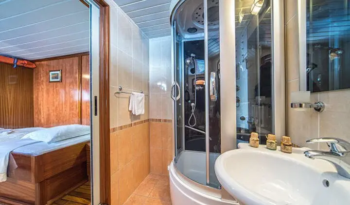 Cabin aboard Luna: king bed with wooden storage, ensuite bathroom door, sea view light