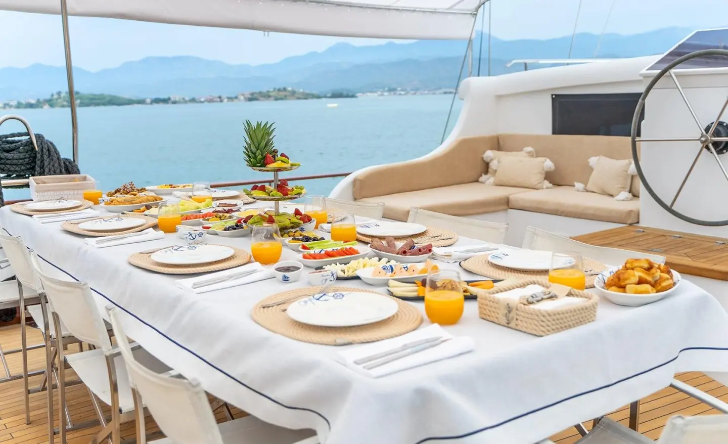 Table set for dining on a yacht deck, with plates, glasses, and orange juice