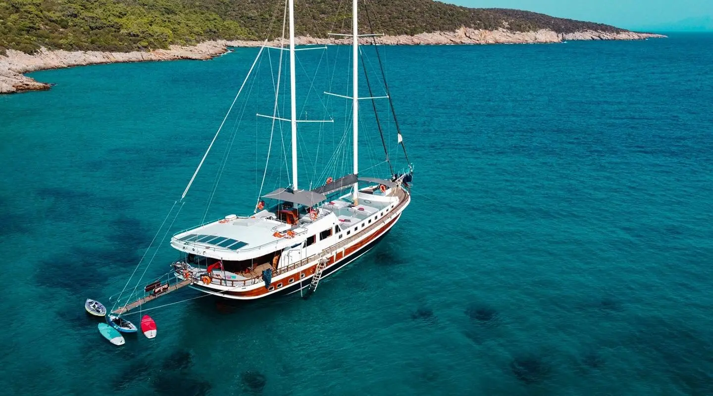 Yacht Bodrum Queen anchored in clear turquoise harbor at sunset