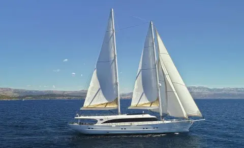 Two tall masts with white sails on a large luxury sailing yacht at sea