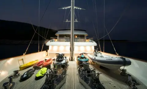 Meira yacht bow deck at night, marina lights glow, deck chairs and ropes visible