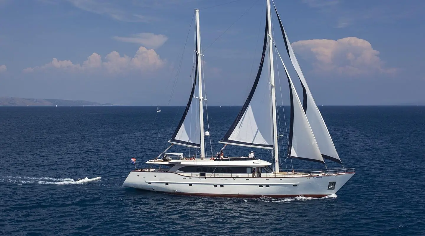 Navilux motor yacht with sails set, gliding on calm blue sea near clear sky