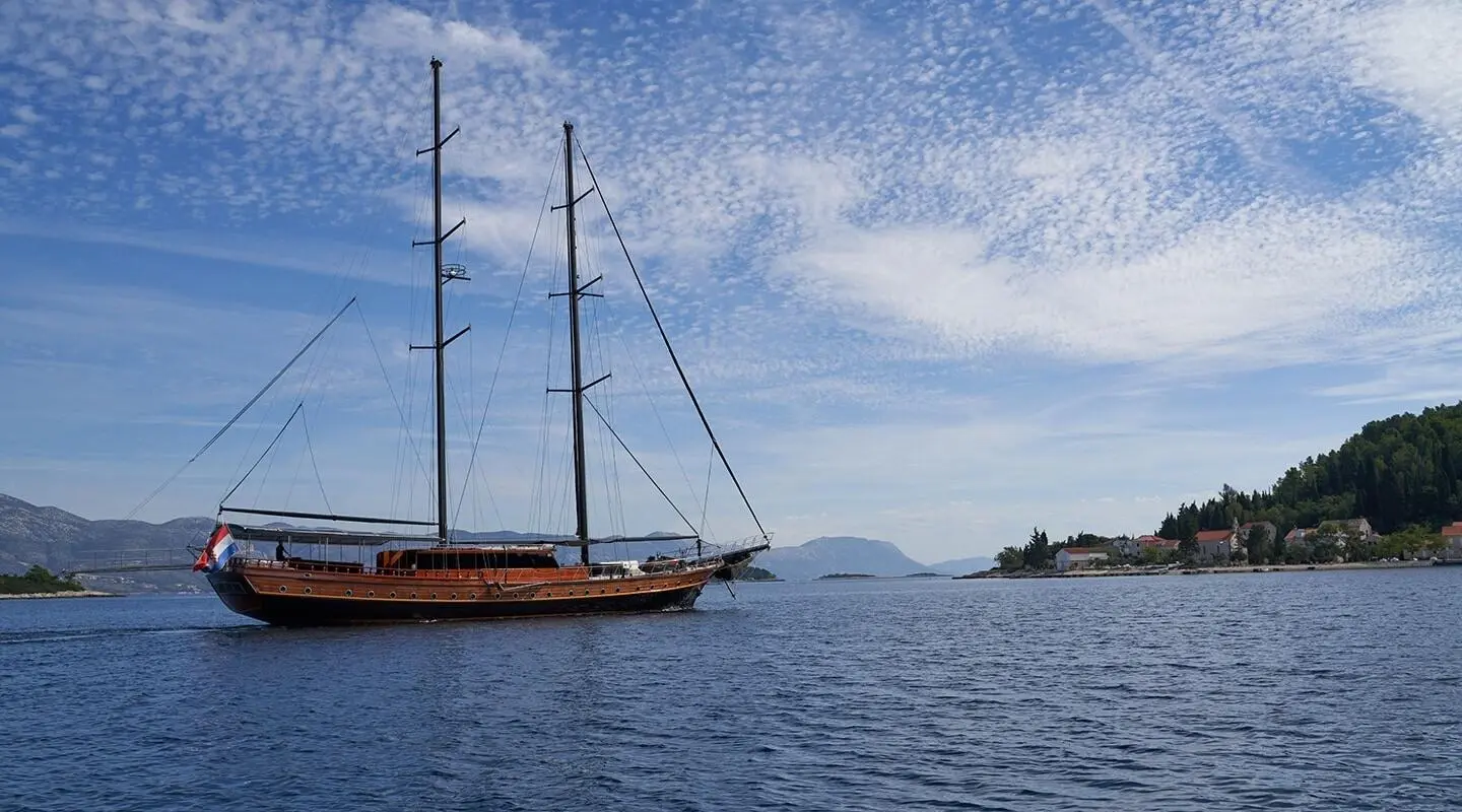 Gulet Stella Maris anchored on calm blue sea with sails lowered by the hull