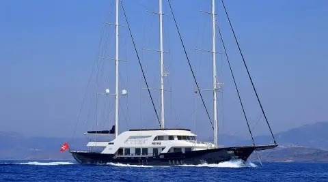 Meira yacht with white hull and tall masts anchored in blue sea