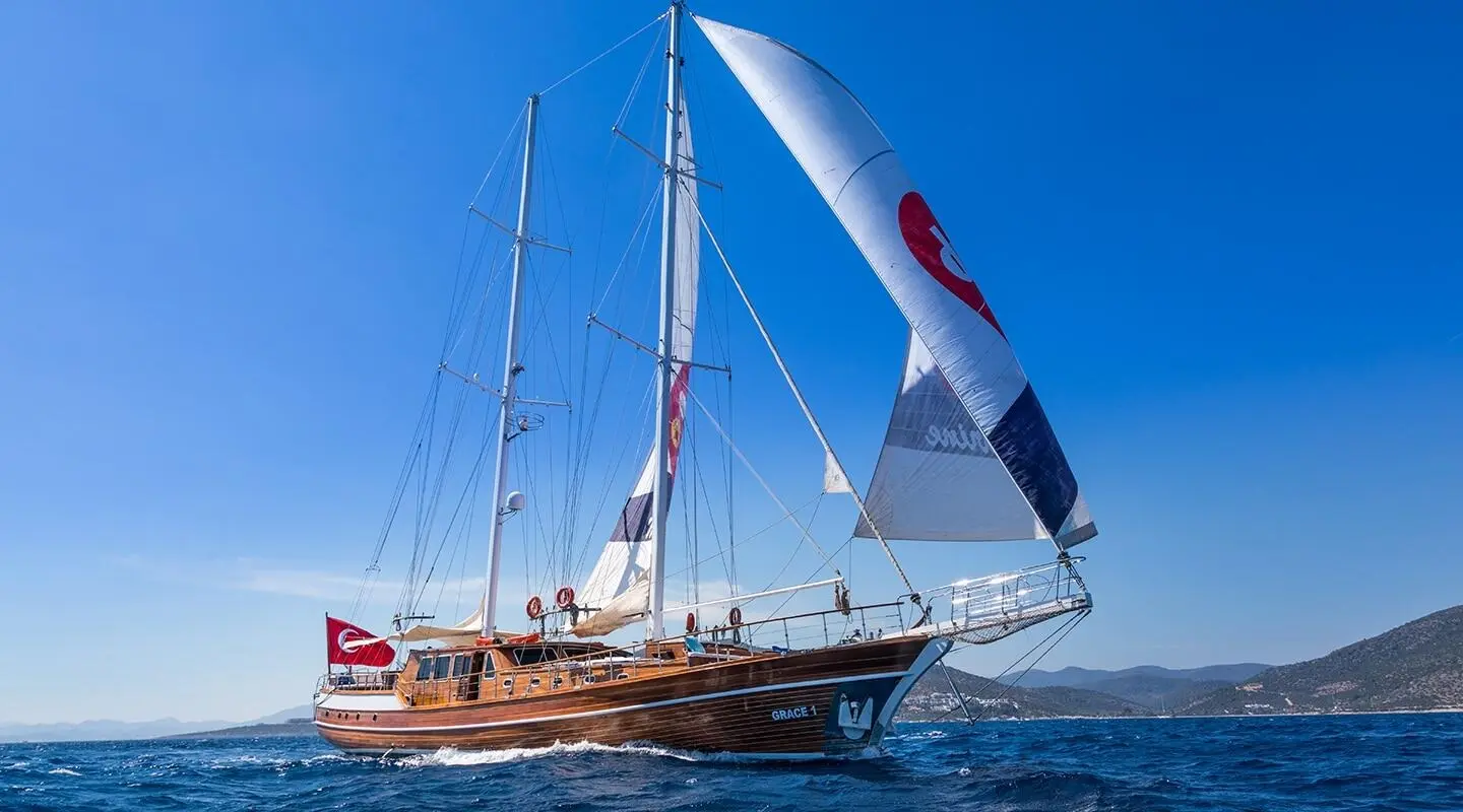 Grace 1 yacht with sails raised, anchored near calm blue sea at sunset