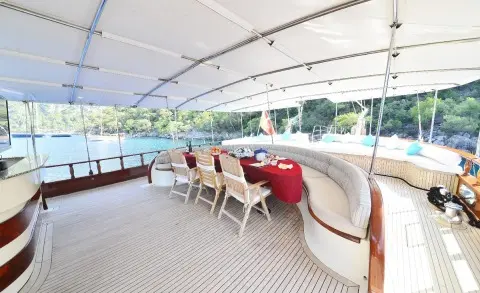 Yacht Berrak Su deck area with seating and sunshades at sunset harbor