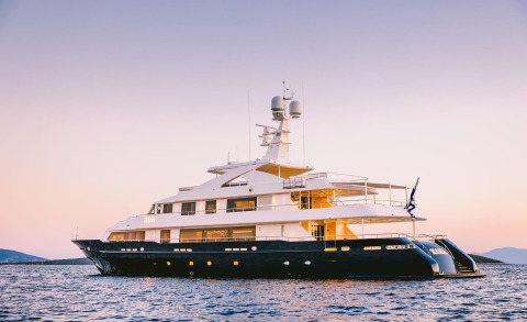 Large yacht with white superstructure and dark hull at sunset