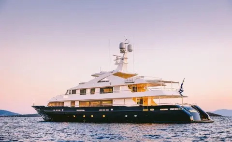 Xana yacht at sunset with white hull and multiple decks on calm water