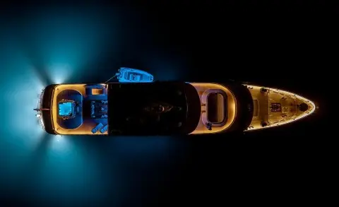 Aerial view of Freedom luxury motor yacht anchored at night with blue water glow