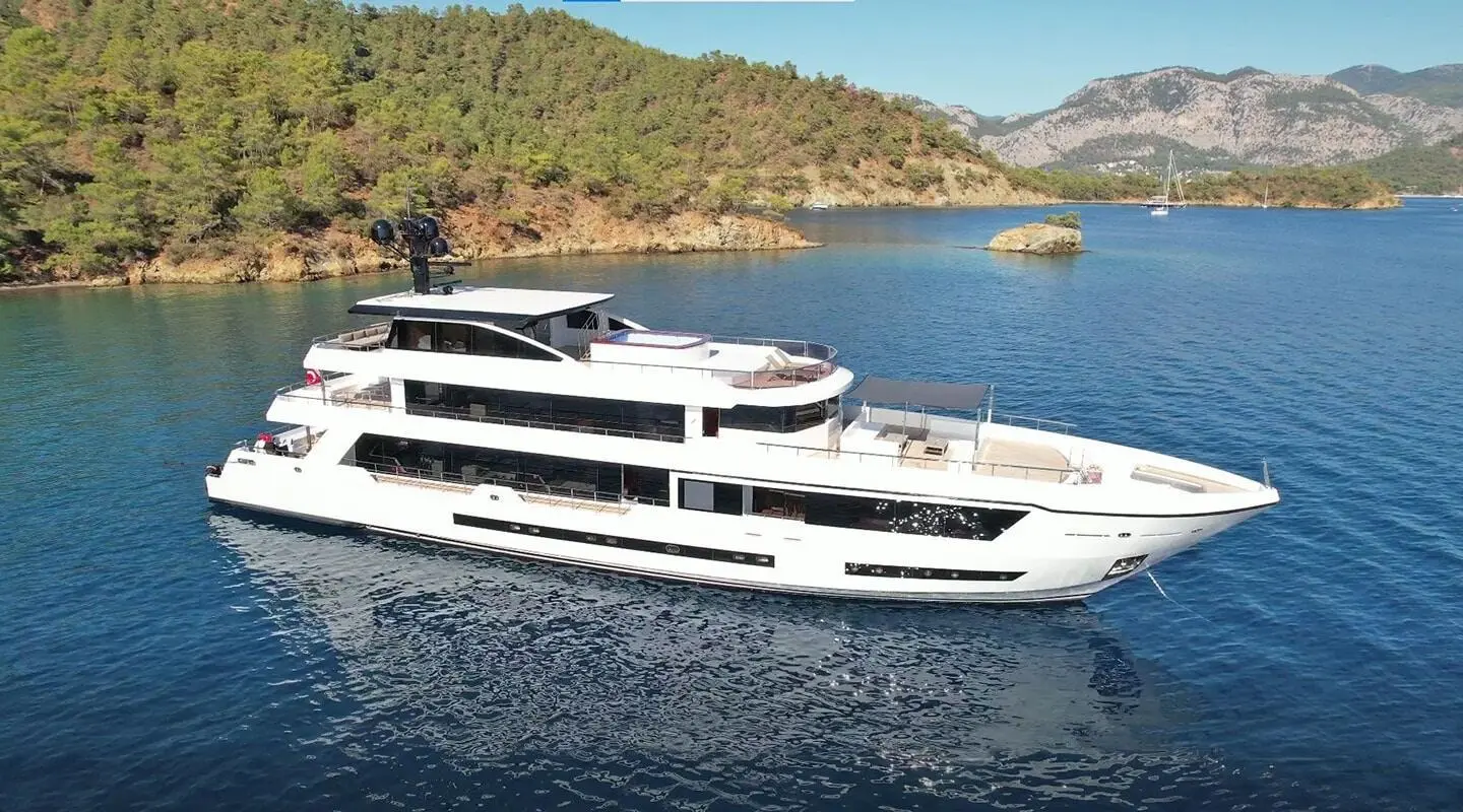 Ocean Breeze luxury motor yacht anchored near rocky coastline on calm blue sea