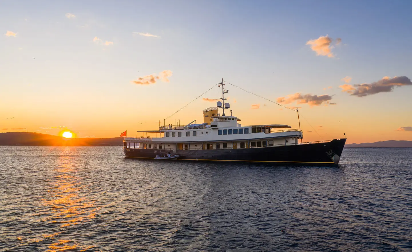 Seagull II yacht at sunset with calm water and orange sky