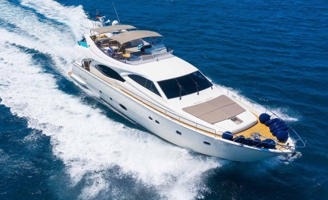 White motor yacht cruising at speed with a large sunbathing area on the bow
