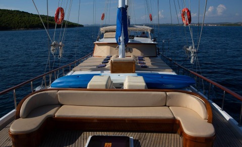 Malena sailing yacht deck view with beige lounge seating and blue safety equipment on a calm sea