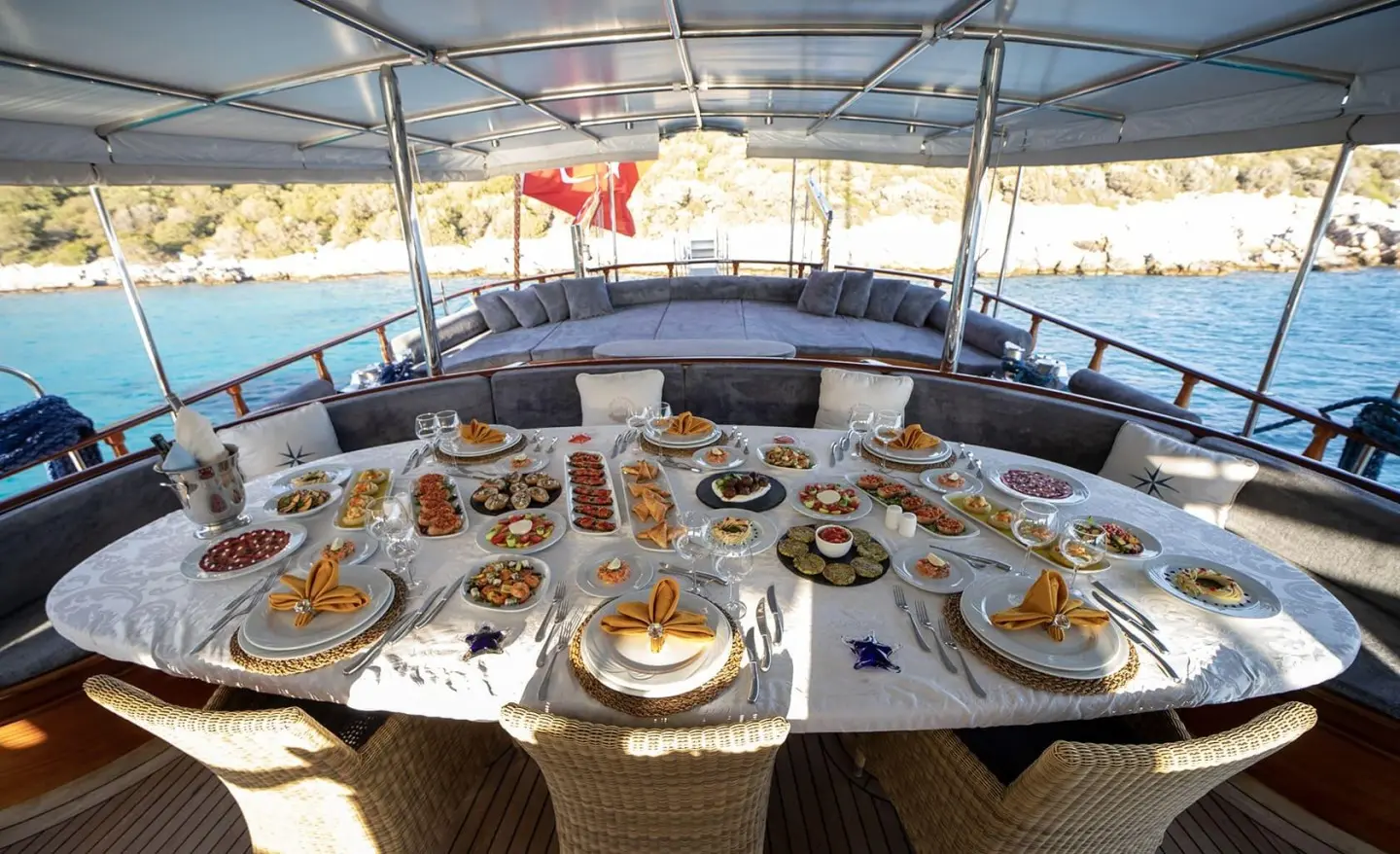 Arif Kaptan A yacht dining table set for guests on deck with dishes