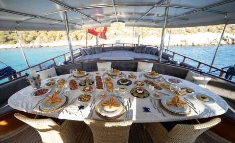 Arif Kaptan A yacht dining table set for guests on deck with dishes