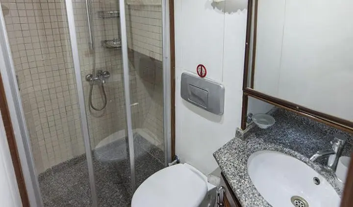 Faralya cabin interior: compact shower, toilet, and granite sink in a sleek yacht