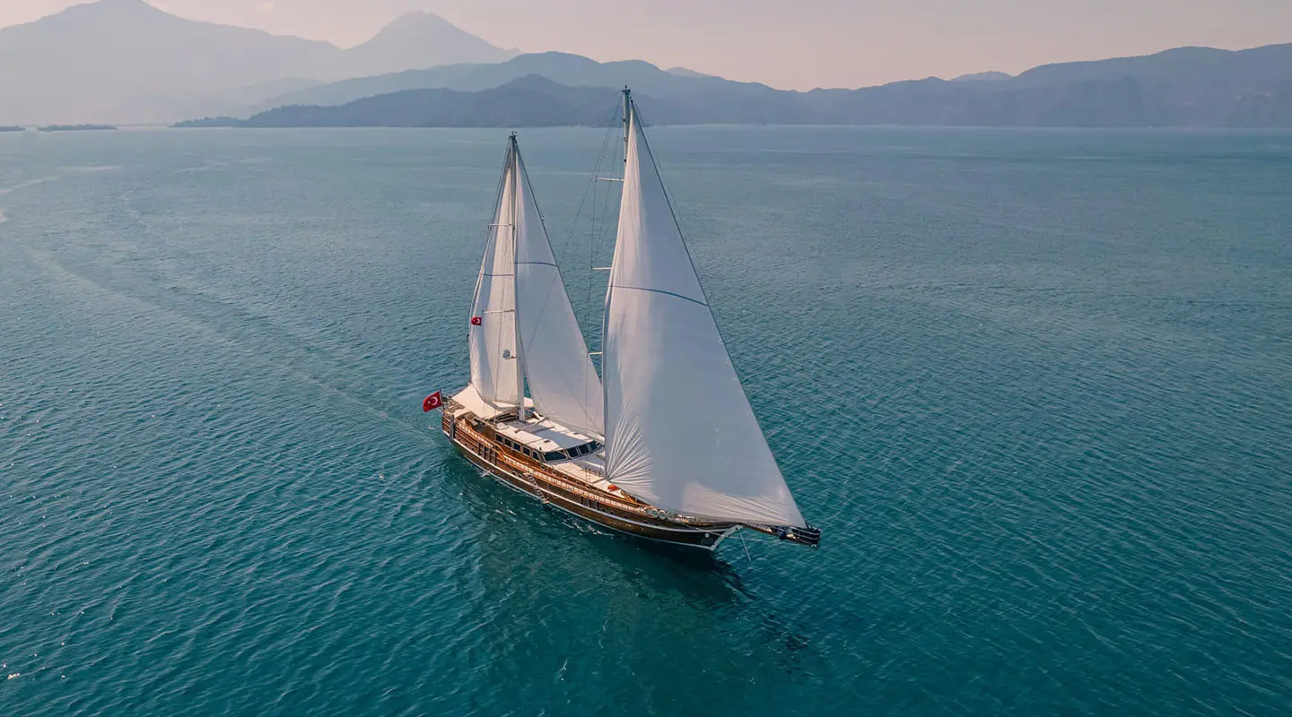 A gulet sailing yacht Lycian Queen glides on calm blue sea under clear sky