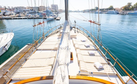 View from the deck of a yacht with striped sunbeds along the sides and calm water nearby