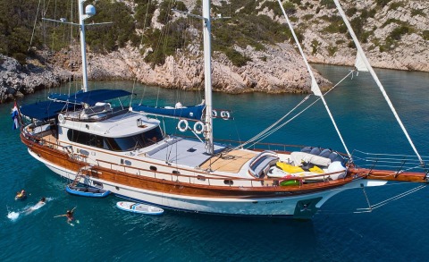Lotus 27m luxury sailing yacht anchored in turquoise cove with rocky cliffs