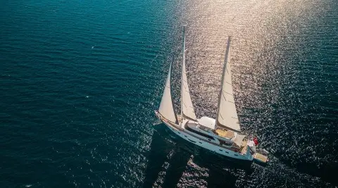 Top-down view of a white sailing yacht Angelo III anchored near blue water