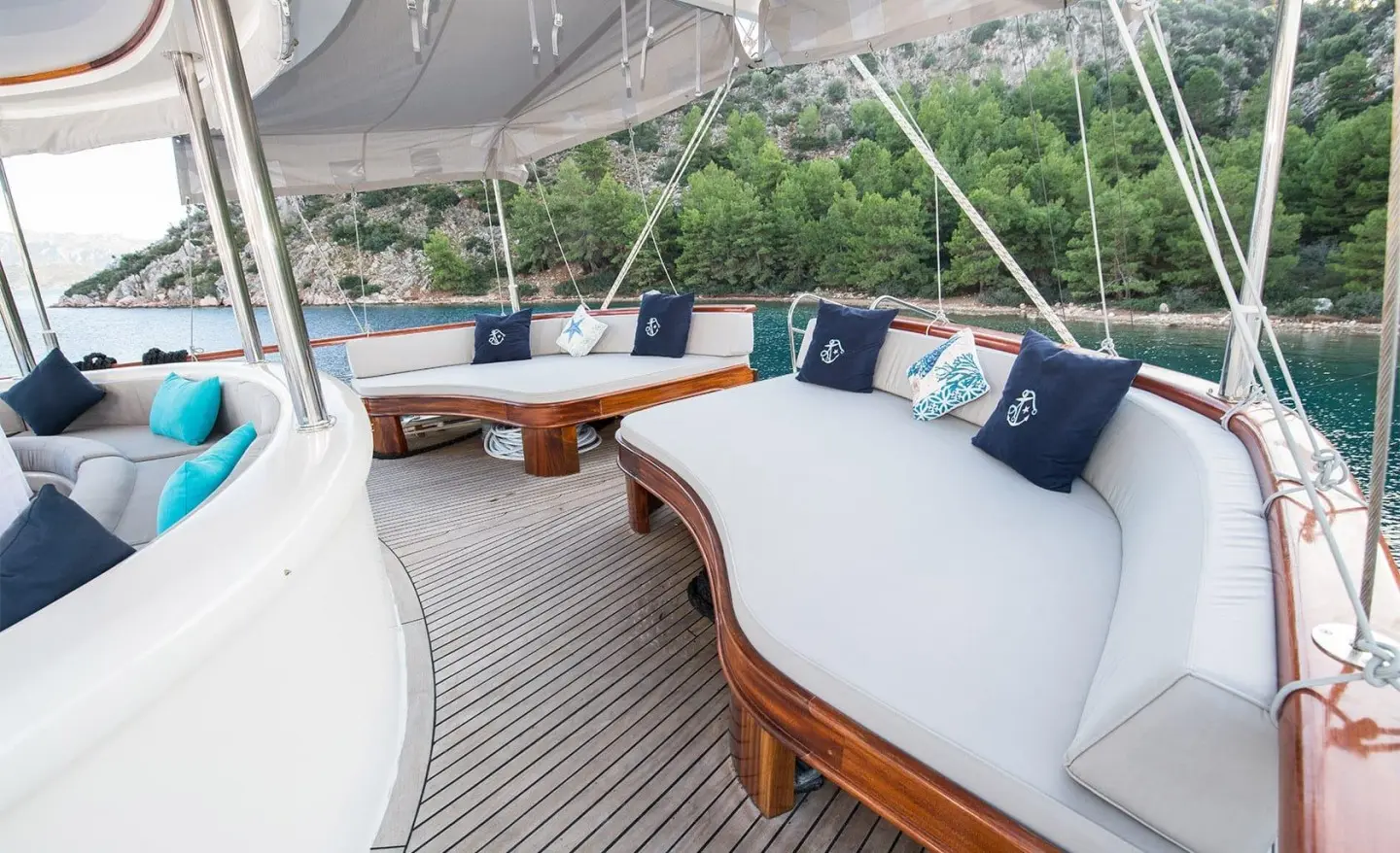 Vista Mare yacht deck seating on teak with white cushions and navy pillows by the water