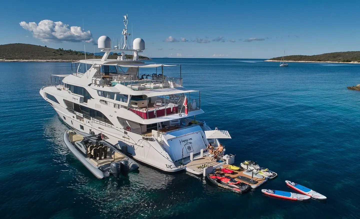 Bright multi-deck luxury yacht named Happy Me docked in calm blue sunset water