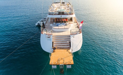 A luxury yacht's aft deck and seating area visible on calm sea