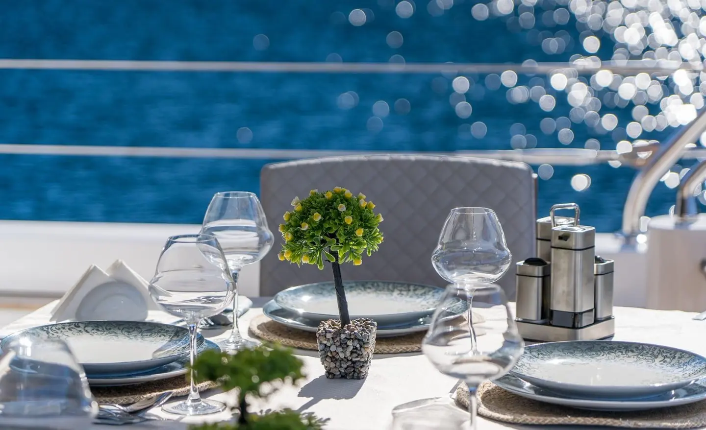 Table set with plates and glassware on a yacht deck overlooking the sea
