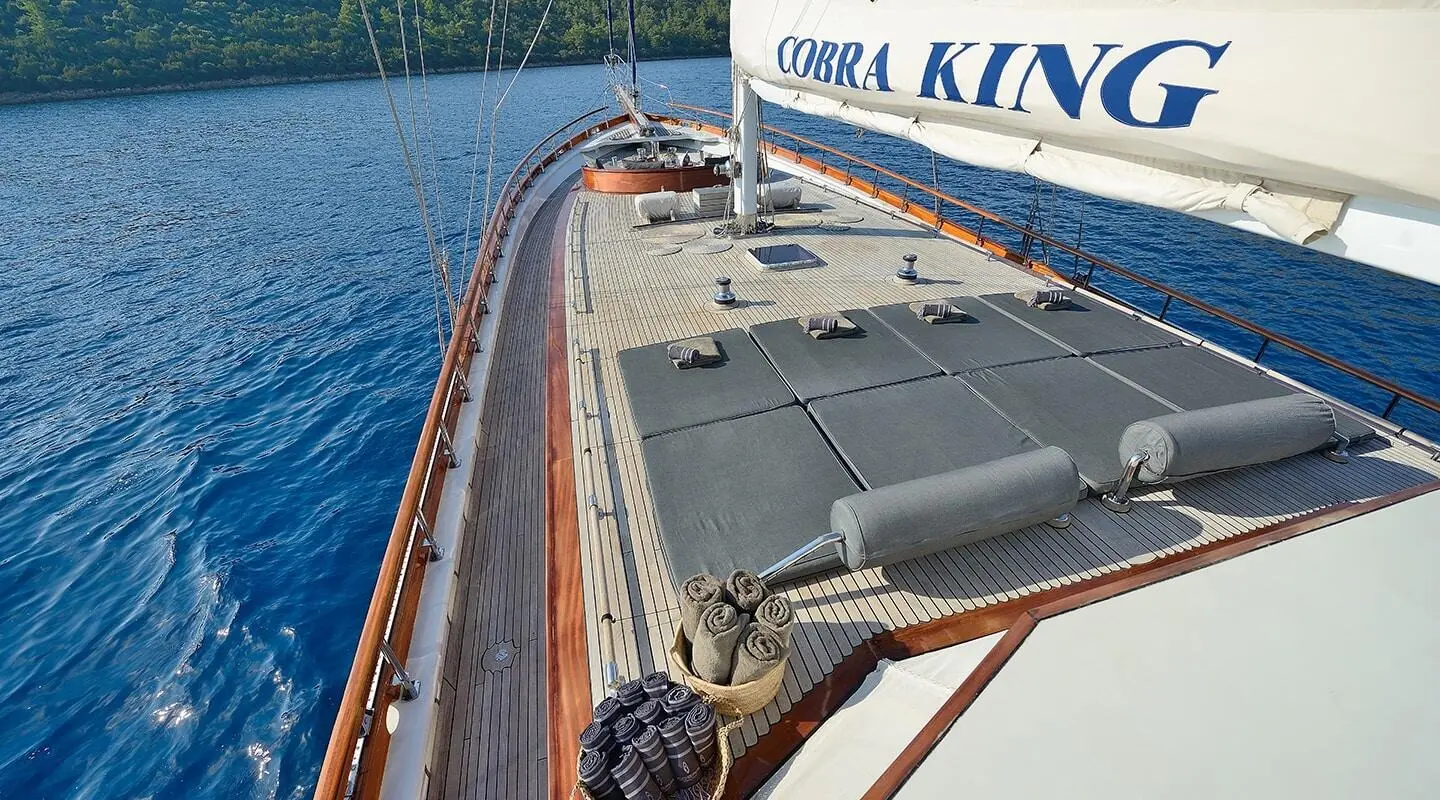 Cobra King yacht deck with polished wood railing and sunlit calm sea