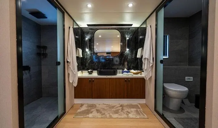View of a yacht cabin with a large bed, wooden floor, and ensuite bathroom doorway
