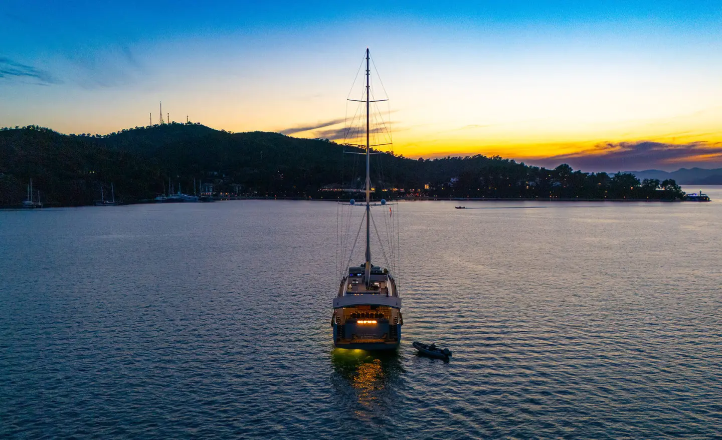 King Of The Sea yacht anchored at sunset on calm water, silhouetted hull