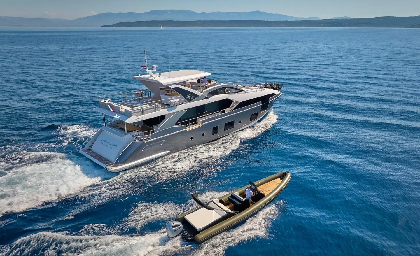 Yacht Aluminia Too cruising blue sea with a small tender nearby