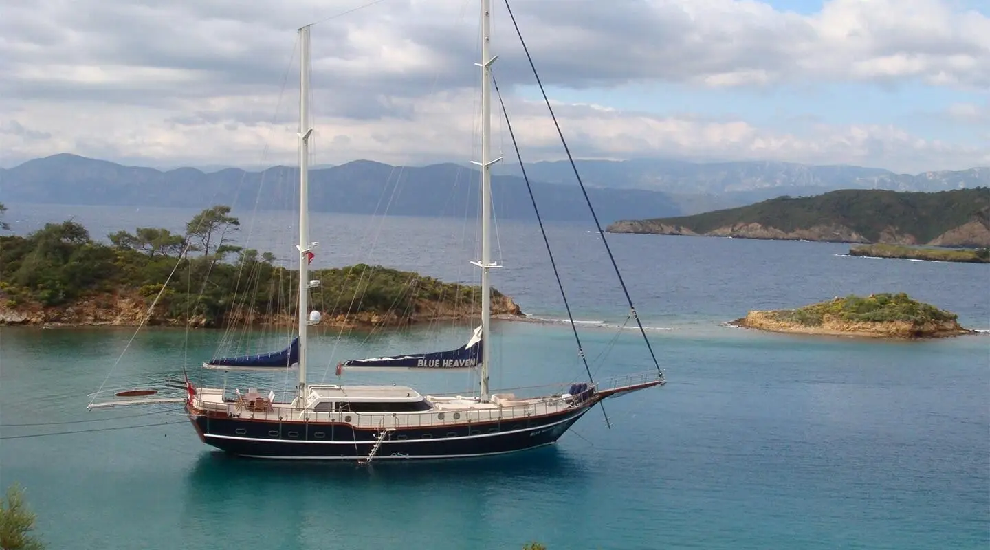 Blue and white sailing yacht anchored in turquoise calm water