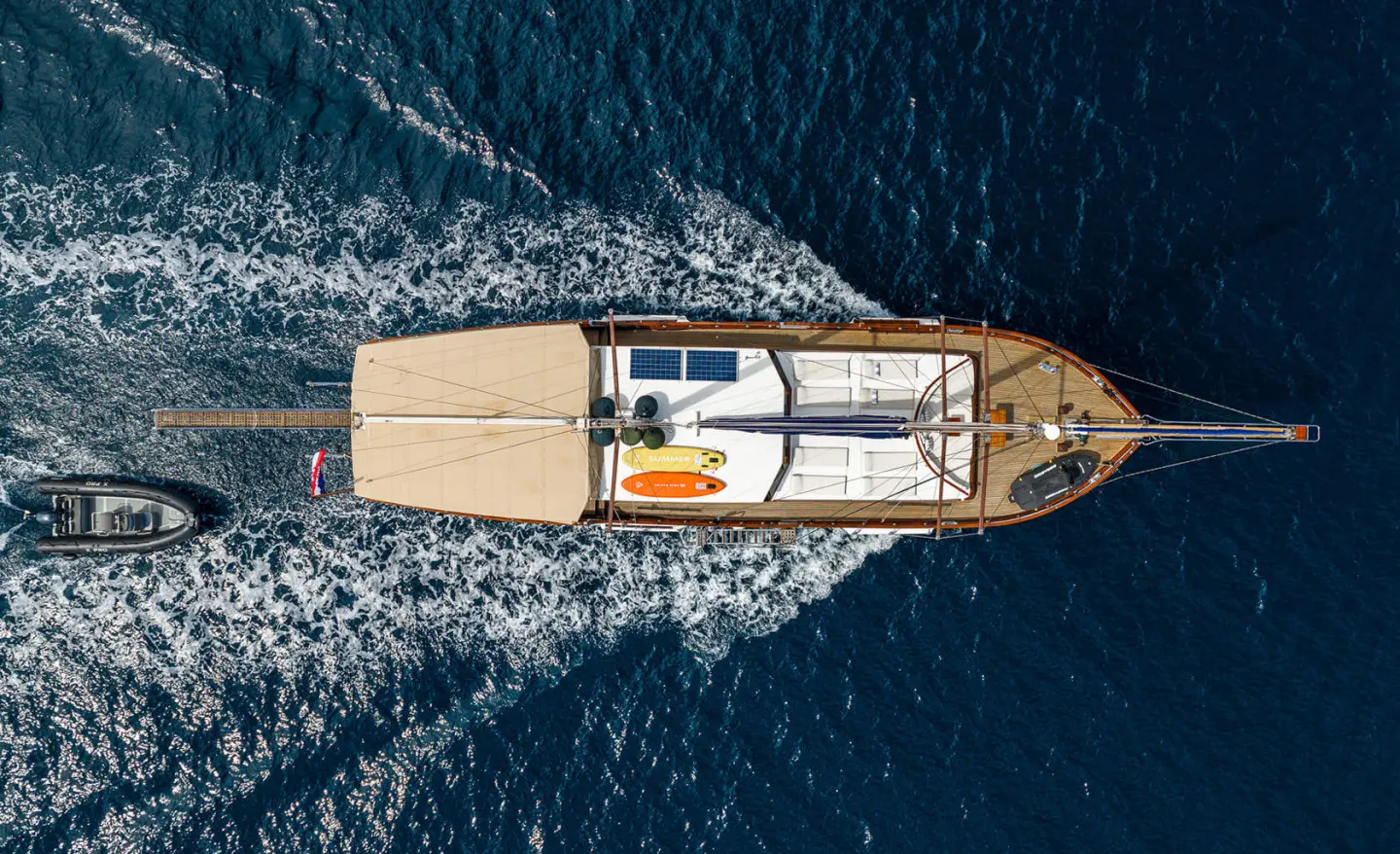 Top-down view of a luxury yacht named Eleganza cruising blue sea at sunset