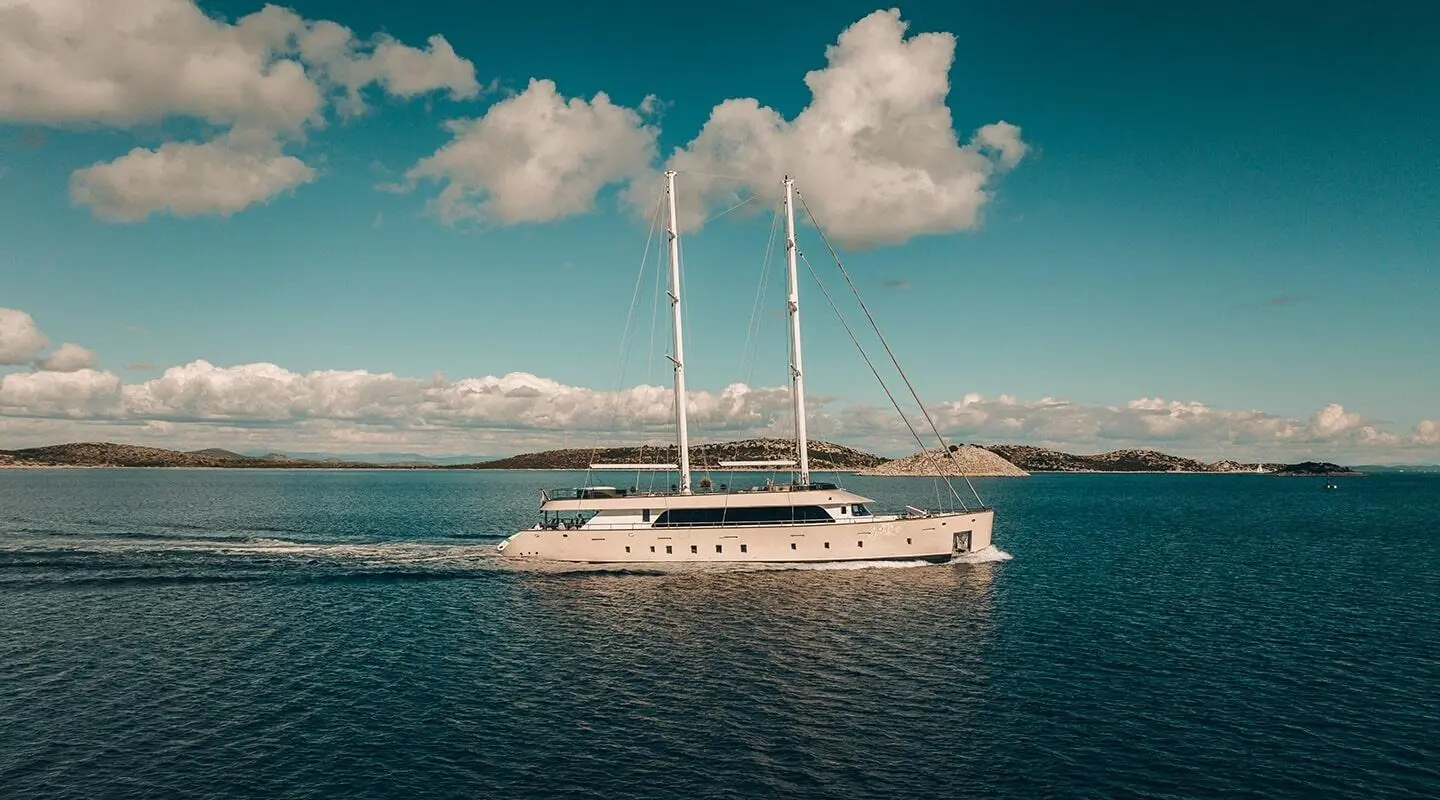 White motor-sail yacht with two masts sailing on calm blue water