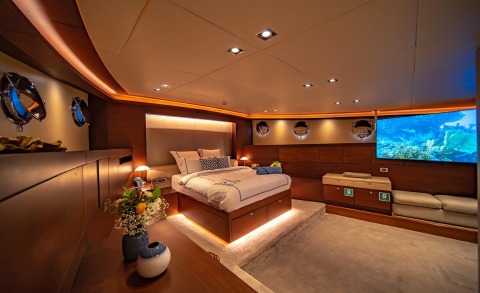 Double Eagle luxury yacht master cabin with bed, ambient lighting, portholes, and a large screen