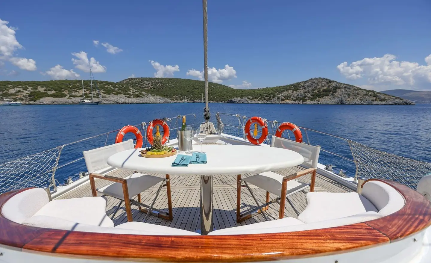 Gazella yacht bow with lifebuoys on deck overlooking calm blue sea at sunset