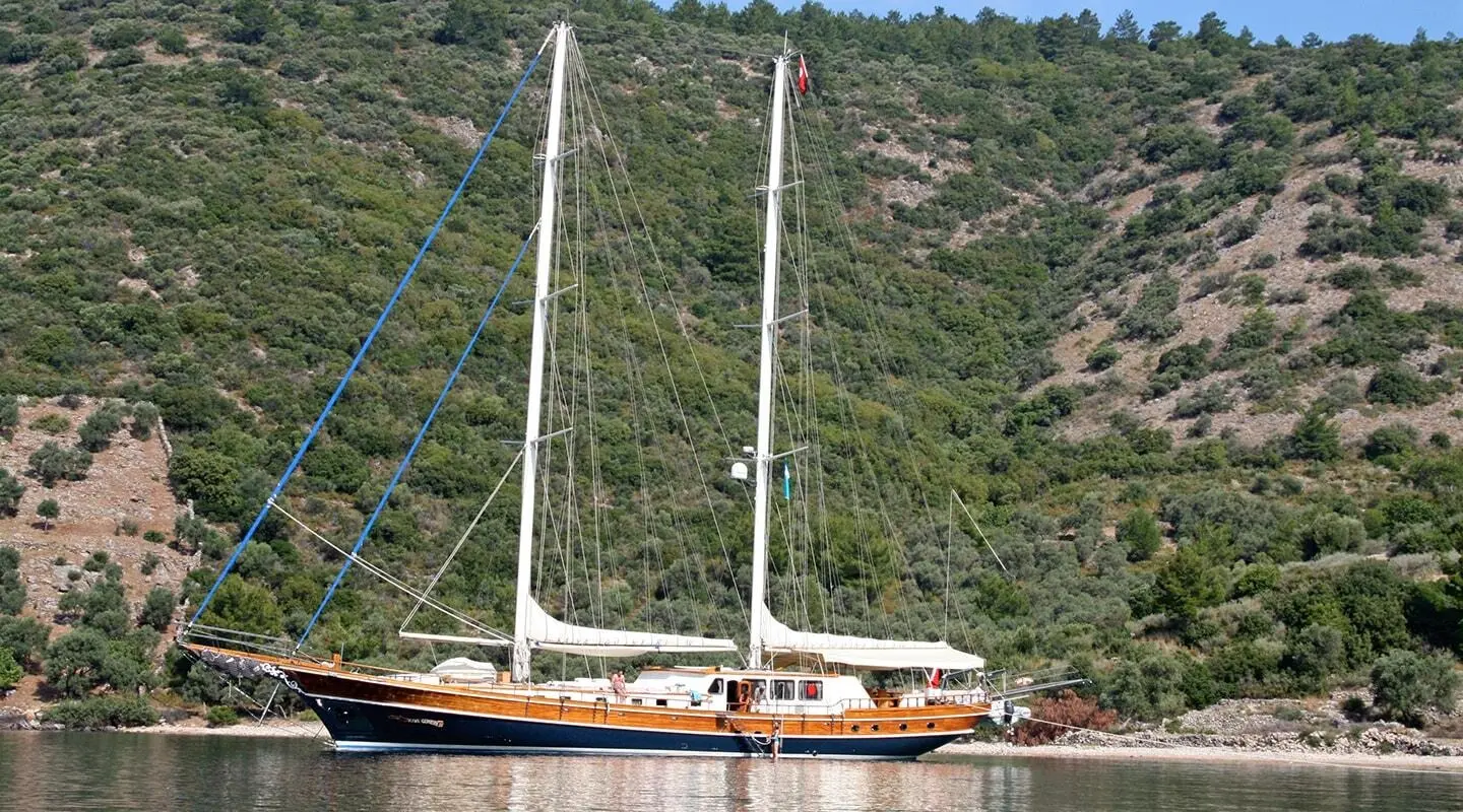 Kaya Guneri 4 sailing yacht anchored near a rocky, forested coastline