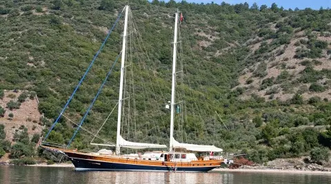 Kaya Guneri 4 sailing yacht anchored near a rocky, forested coastline