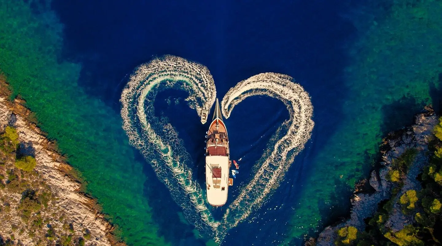 Aerial view of gulet Cesarica yacht at sea with a V-shaped wake
