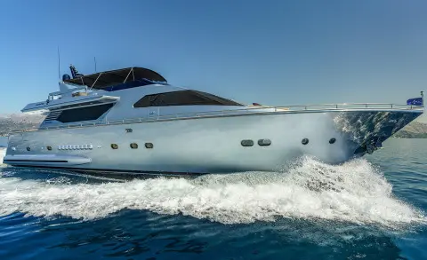 Phantom motor yacht cruising on blue sea with wake behind, clear sky