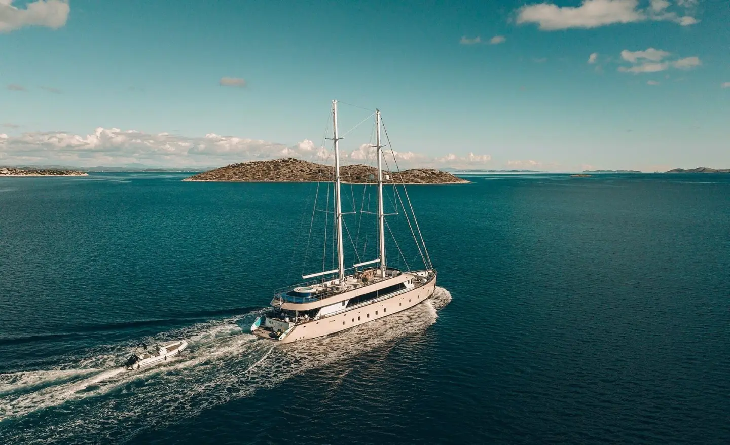 Maxita motor yacht cruising on calm blue sea, wake visible behind vessel