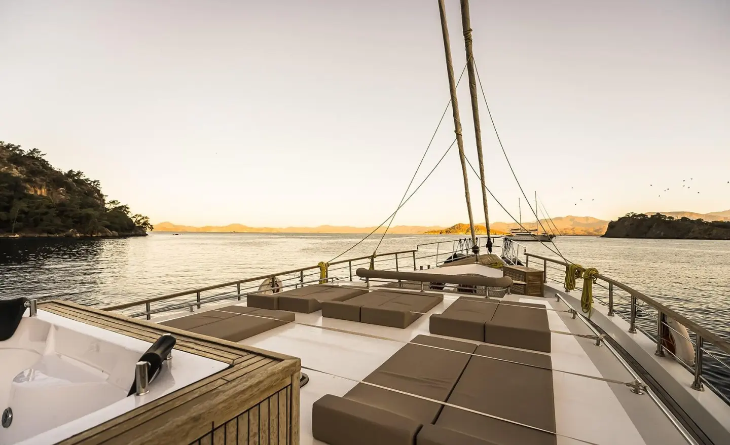 Sunlit yacht deck with brown loungers and railing overlooking calm sea