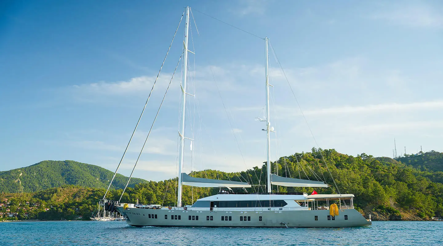 King Of The Sea yacht moored at sunset with sails lowered and calm water