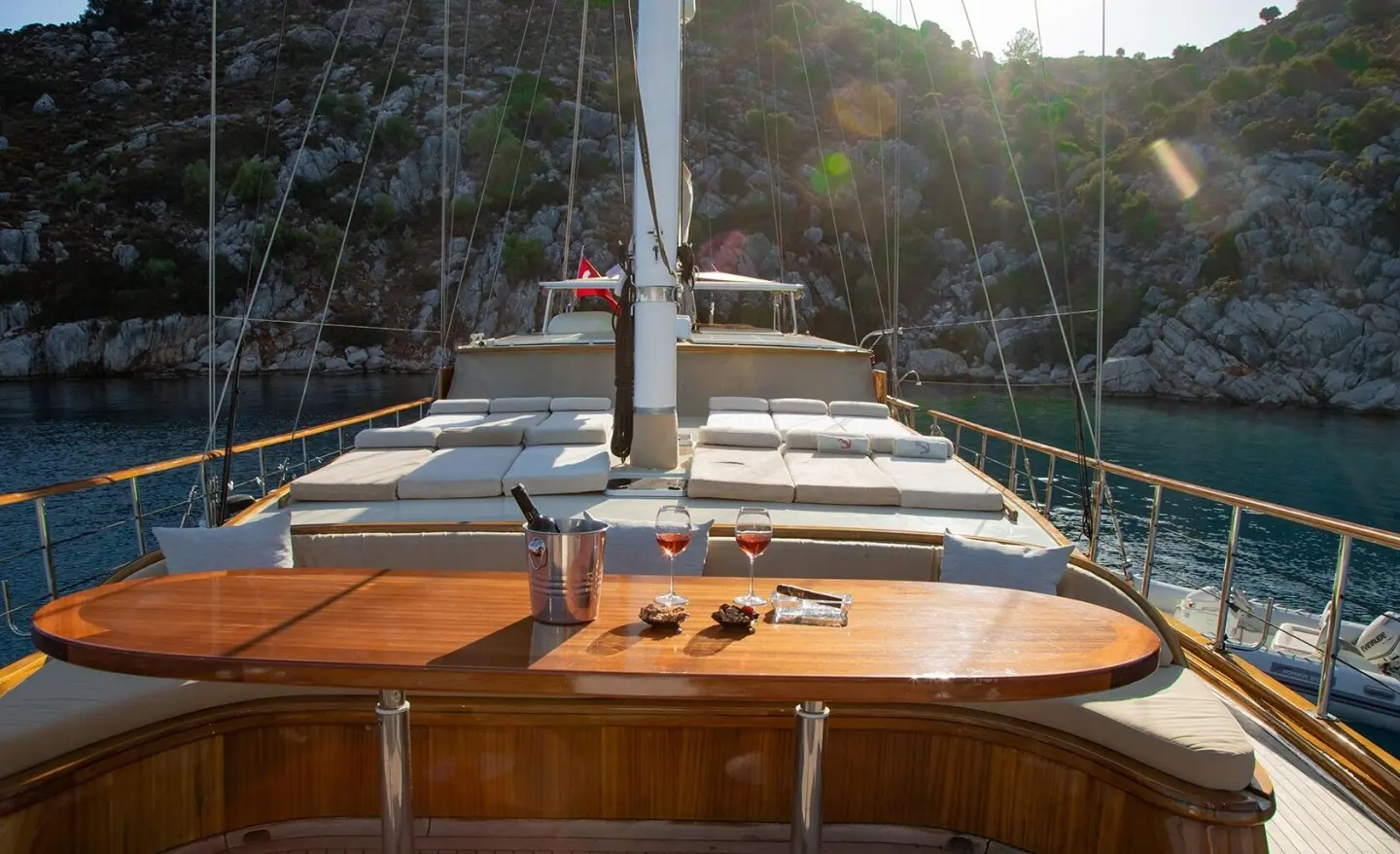 Sailing yacht Derin Deniz deck with wooden seating, ropes, and sunset glow